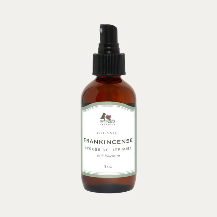 An amber spray bottle of 123 Farm Organic Stress Relief Mist with Rosemary is on a white background. Available at Luca Essentials in Los Angeles.