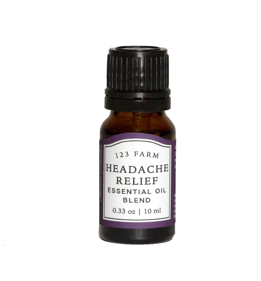 An amber bottle of "123 Farm Headache Relief Essential Oil" with a label indicating the blend of essential oils including lavender, peppermint, frankincense, marjoram, rosemary, and grapefruit. Available at Luca Essentials.
