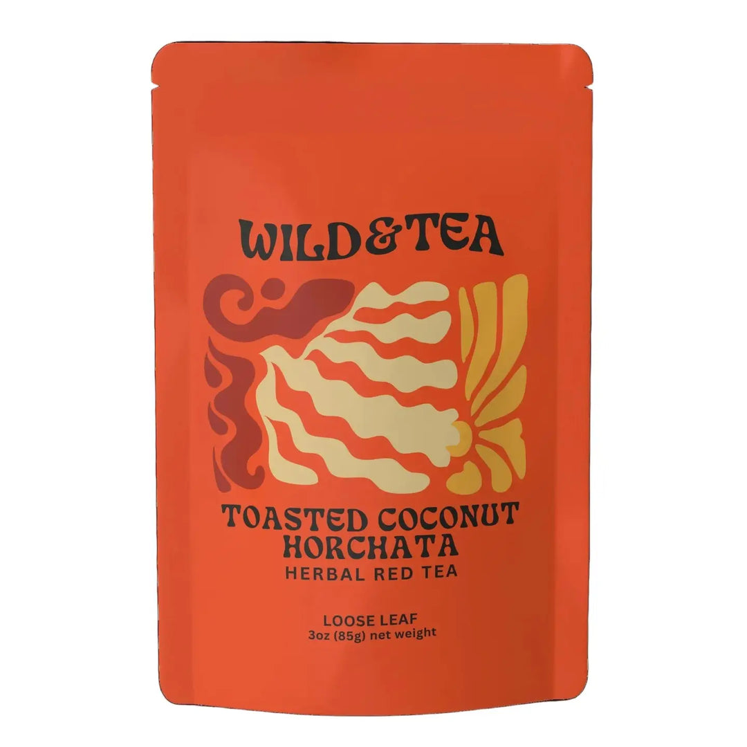 A bright orange stand-up pouch of Wild & Tea Toasted Coconut Horchata Loose Leaf Herbal Red Tea, featuring a stylized graphic of abstract patterns with red and yellow accents. Sold at Luca Essentials in Los Angeles