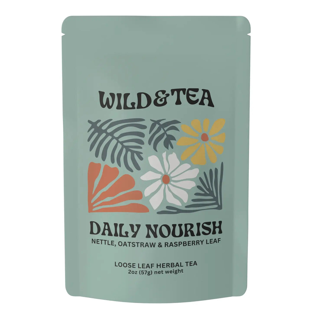 A stand-up pouch of Wild & Tea Daily Nourish loose leaf herbal tea on a plain white background. The pouch is a muted sage green with a colorful illustration of leaves and flowers in orange, yellow, white, and gray, and black text. Available at Luca Essentials in Los Angeles