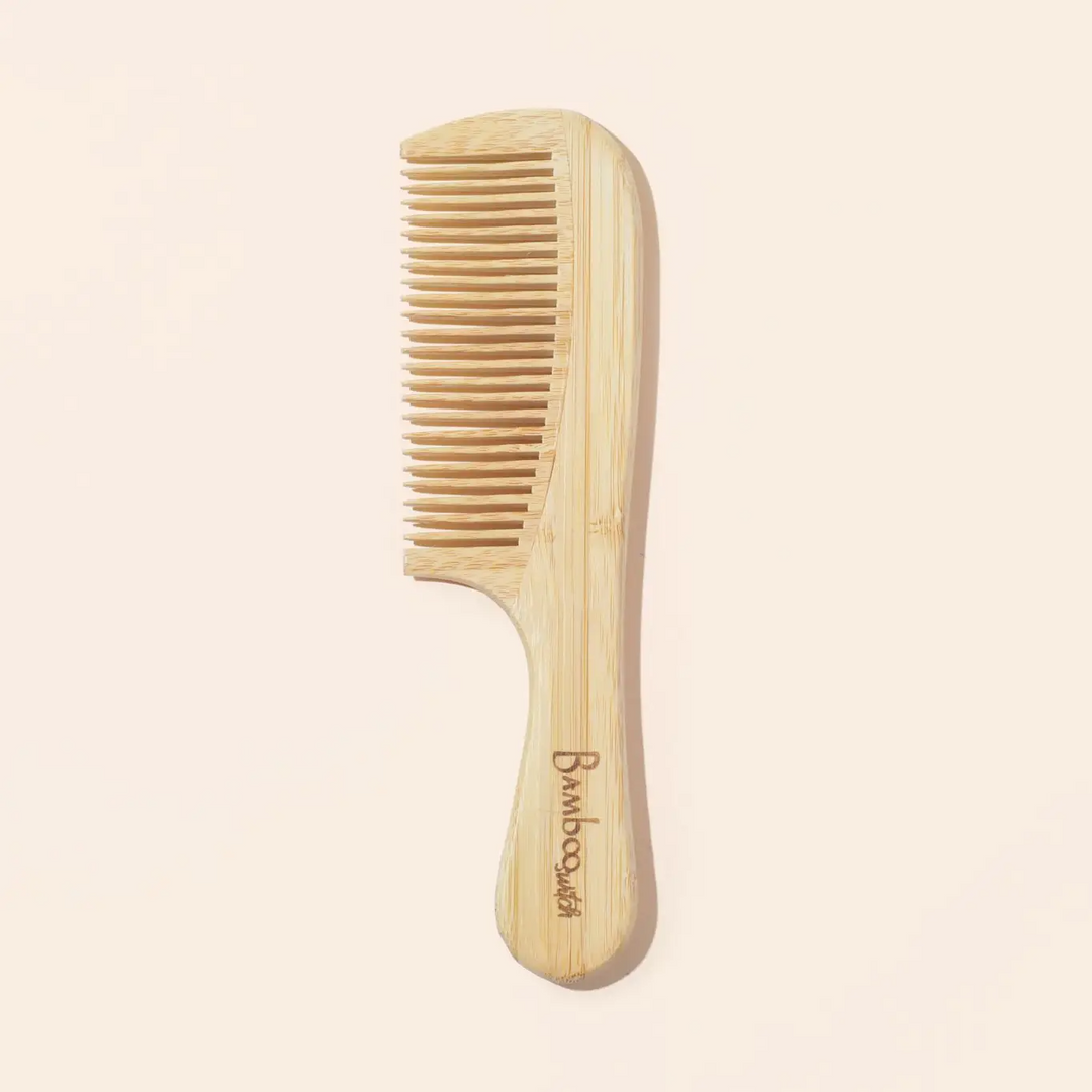 A natural color bamboo handle comb, with the brand name 'Bamboo' inscribed on the handle. Bamboo Switch is available at Luca Essentials in Los Angeles.