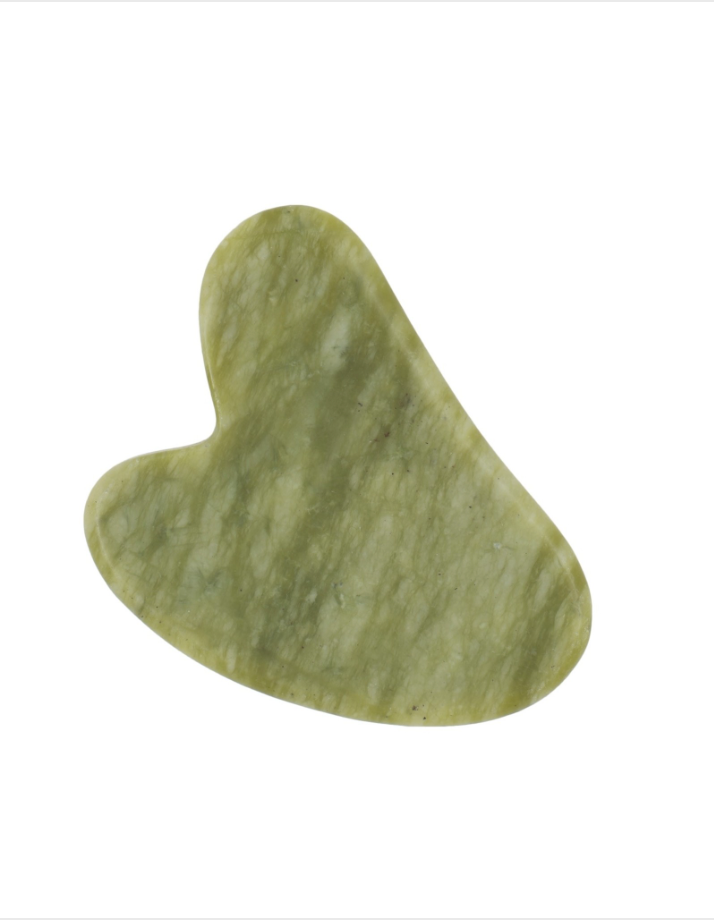 A jade Gua Sha is on a white background. Bamboo Switch is available at Luca Essentials in Los Angeles.