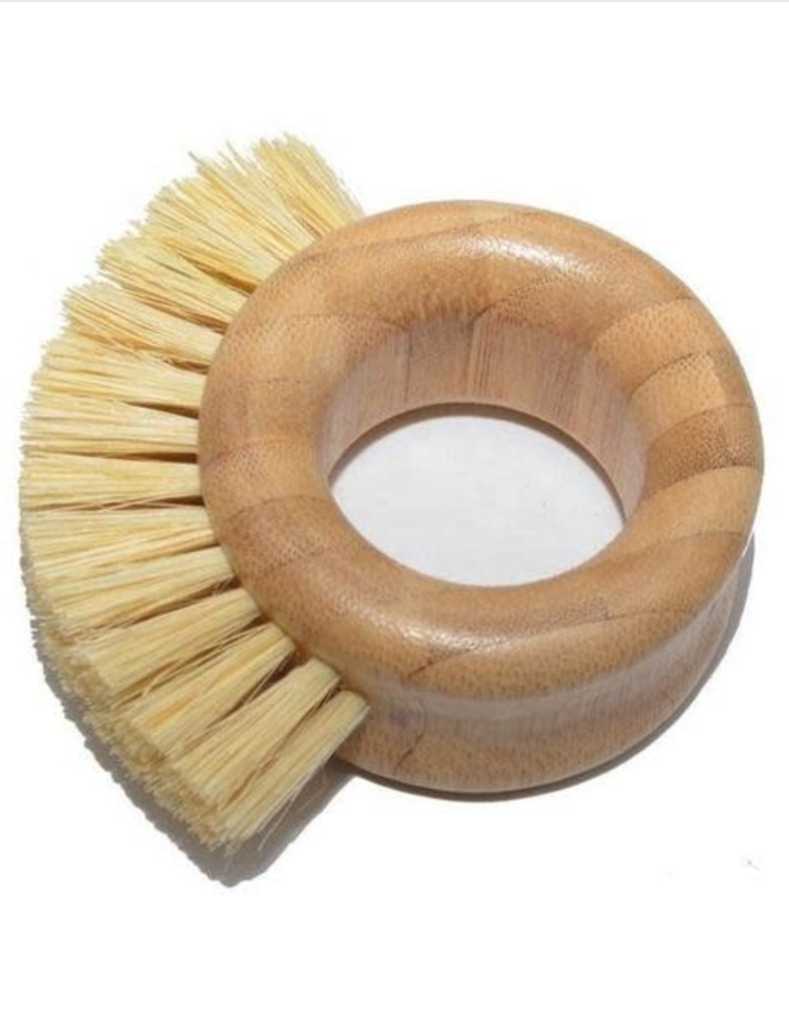 A round bamboo pot scrubber with natural brush fibers  on  white background. Bamboo Switch is available at Luca Essentilas in Los Angeles.