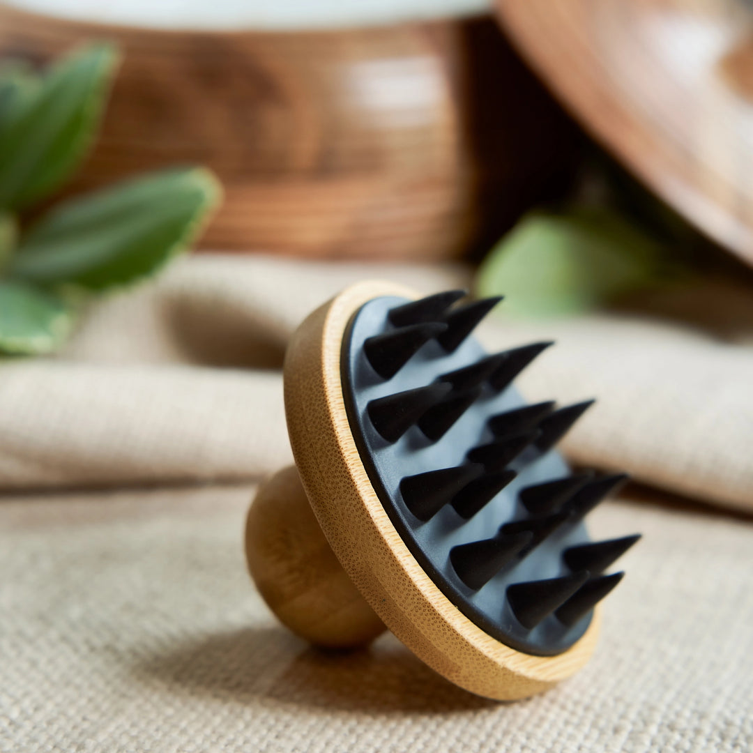 Wooden brush with black bristles on a textured surface. Bamboo Switch is available at Luca Essentials in Los Angeles.