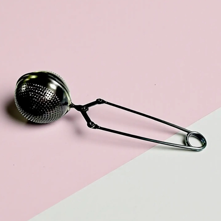Metallic tea ball on a pink and white background. Bamboo Switch is available at Luca Essentials in Los Angeles.