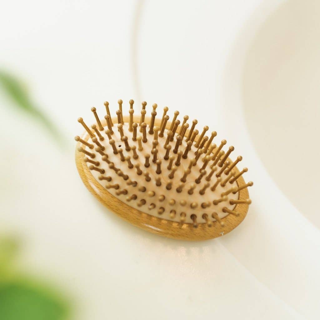 A bamboo brush without a handle with rounded bristles, placed on a white surface, likely a bathroom counter.  Bamboo Switch is available at Luca Essentials in Los Angeles.