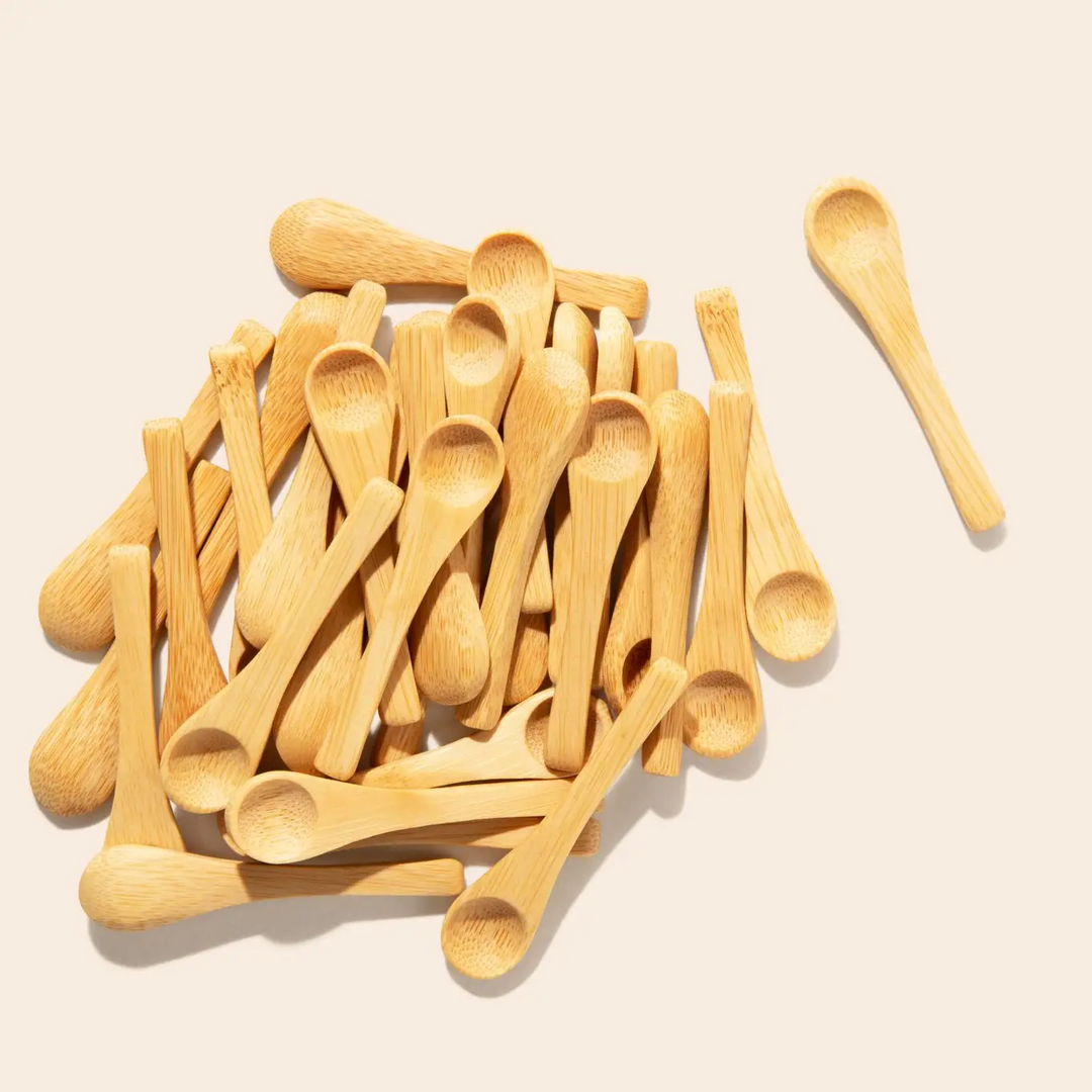 A collection of small bamboo spice spoons scattered on a light background, with one spoon placed beside the pile showing the sleek design. Bamboo Switch is available at Luca Essentials in Los Angeles.