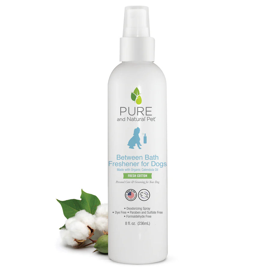 Bottle of Pure and Natural Pet Between Bath Freshener for Dogs on a white background with cotton and leaves. Available at Luca Essentials in Los Angeles.