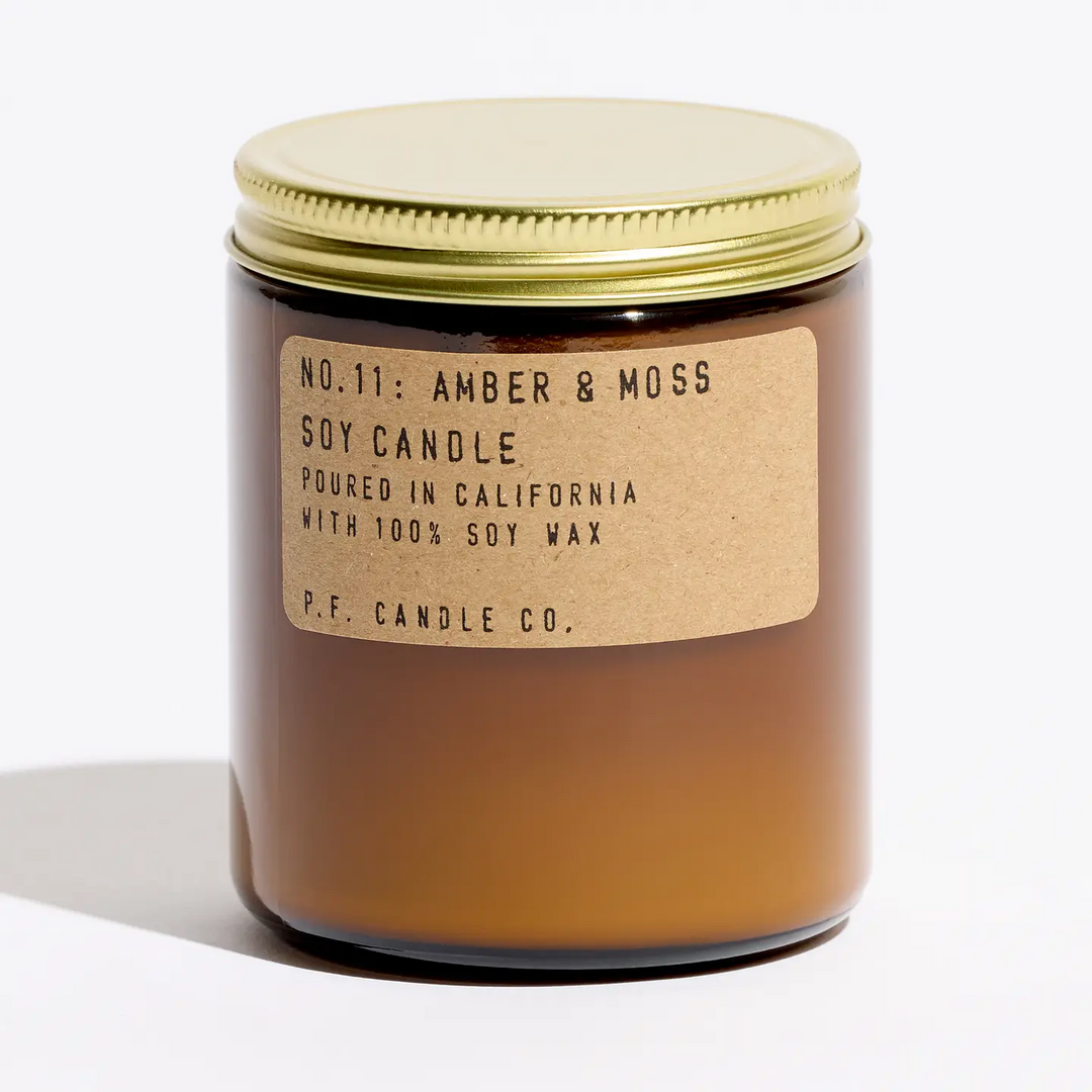 Amber candle with a gold lid and P.F. Candle Co. label on a white background. Available at Luca Essentials in Los Angeles. 