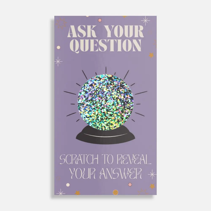 Glowing crystal ball scratch-off card with 'Ask Your Question' text on a purple background. Available at Luca Essentials in Los Angeles. 