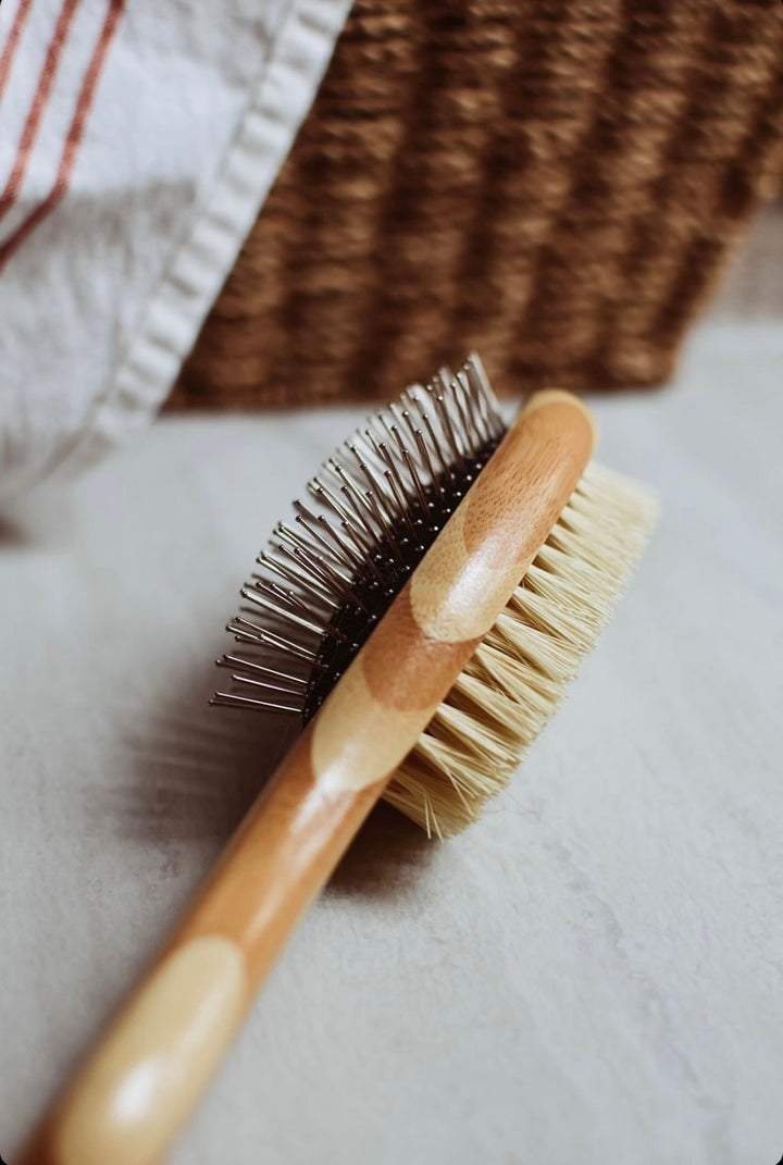 Wooden brush with bristles on a textured surface. Bamboo Switch is available at Luca Essentials in Los Angeles.