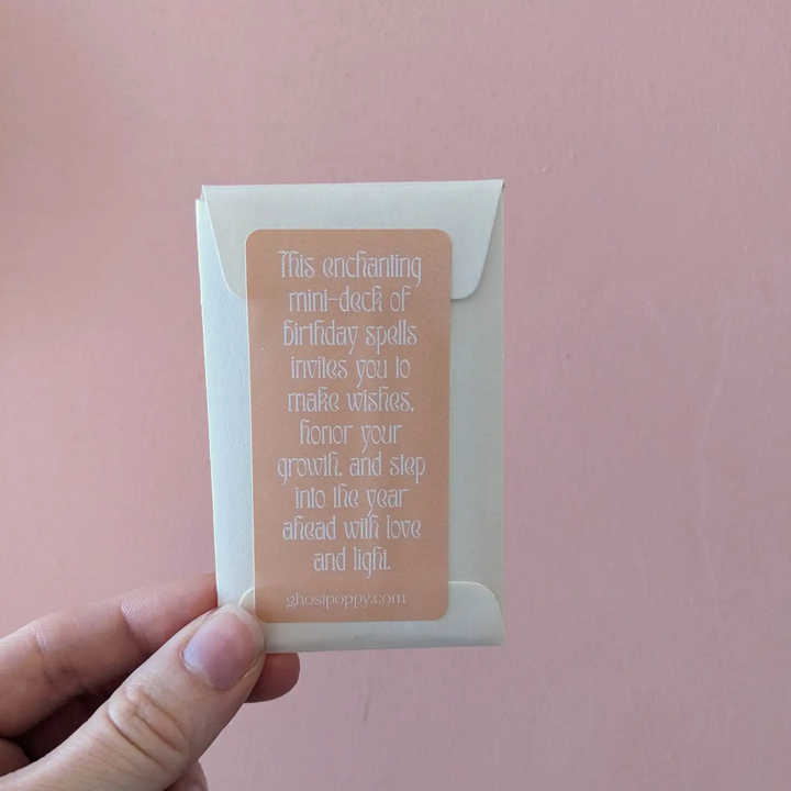 Hand holding a small card with text against a pink background. Available at Luca Essentials in Los Angeles. 