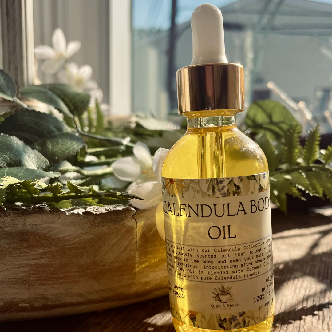 Bottle of calendula body oil with a dropper on a wooden surface with plants in the background. Available at Luca Essentials in Los Angeles. 