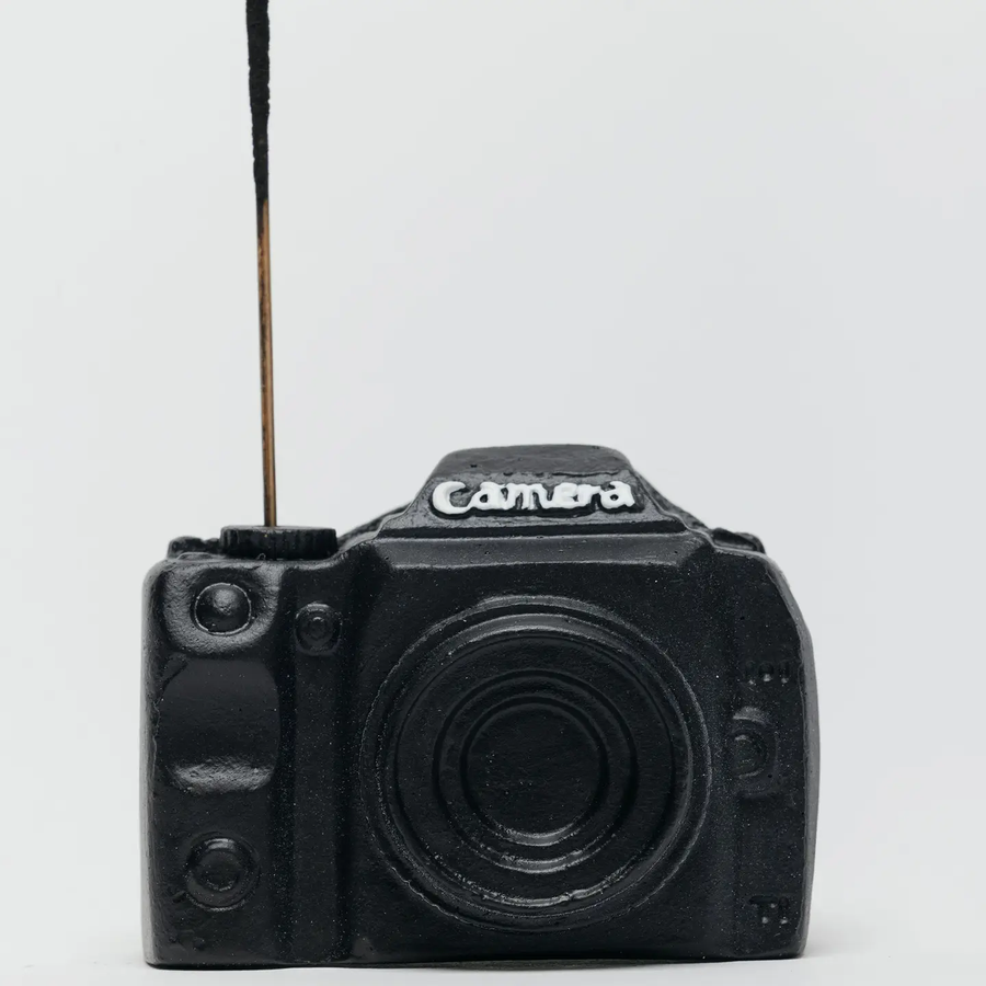 Black camera-shaped object on a light gray background. Available at Luca Essentials in Los Angeles. 