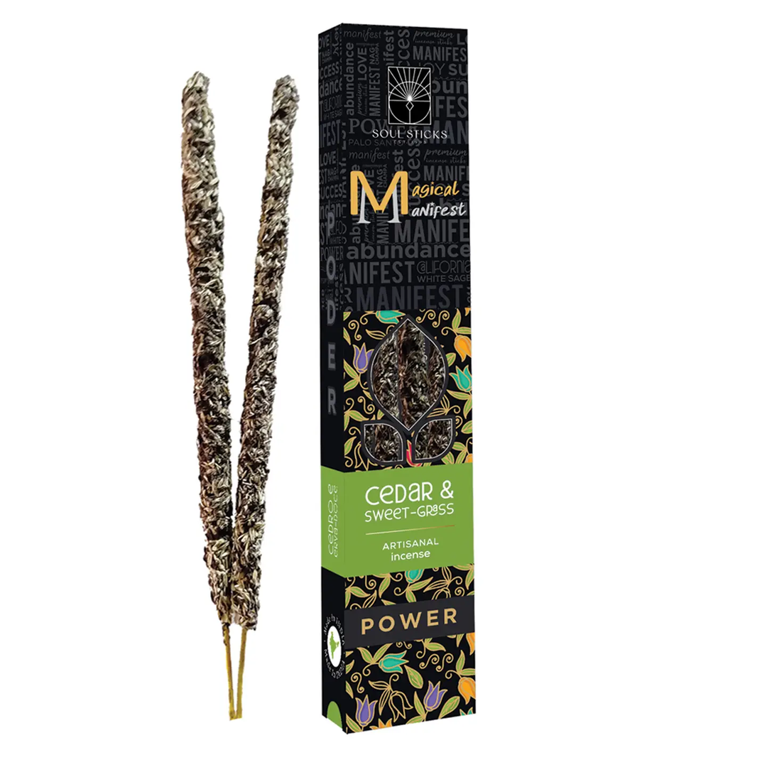 A box of Soul Stuffs 'MAGICAL MANIFEST' incense sticks, Cedar & Sweet Grass, next to two dried incense sticks, on a plain white background. Available at Luca Essentials in Los Angeles. 