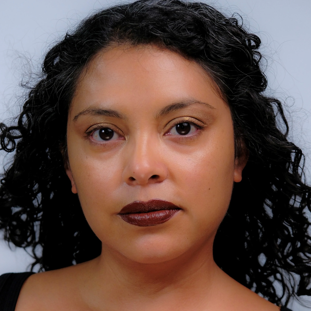 Citrine- Close-up of a tan woman with dark hair and brown lipstick against a neutral background. Available at Luca Essentials in Los Angeles. 