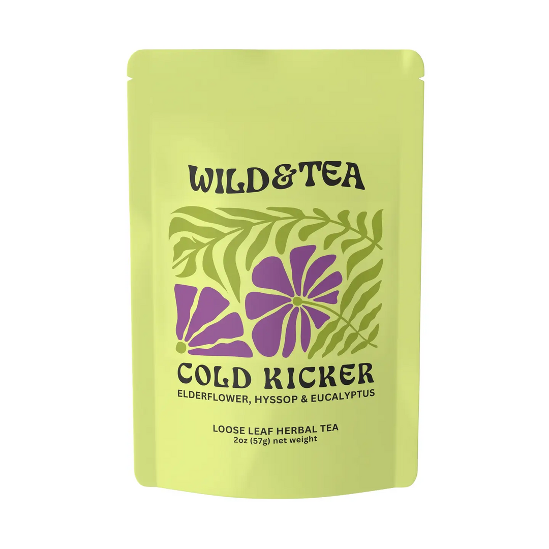 A light yellow-green stand-up pouch of Wild & Tea 'Cold Kicker' loose leaf herbal tea, featuring purple flowers and green leaves on the front, set against a plain white background. Available at Luca Essentials in Los Angeles. 