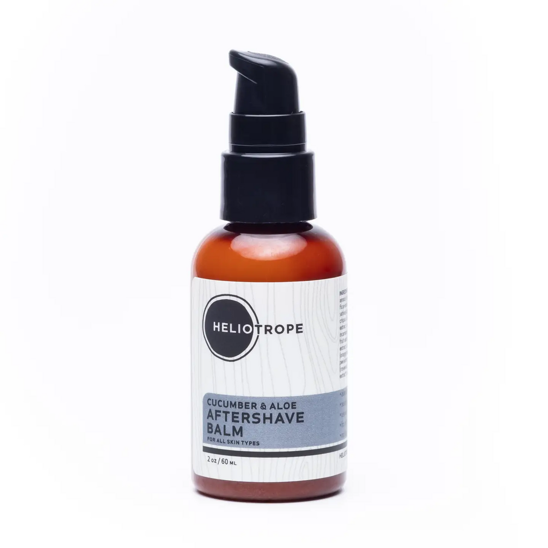 A 2 fl oz amber glass pump bottle of Heliotrope Cucumber & Aloe Aftershave Balm, featuring a black pump and a white and gray label, set against a plain white background. Available at Luca Essentials in Los Angeles. 