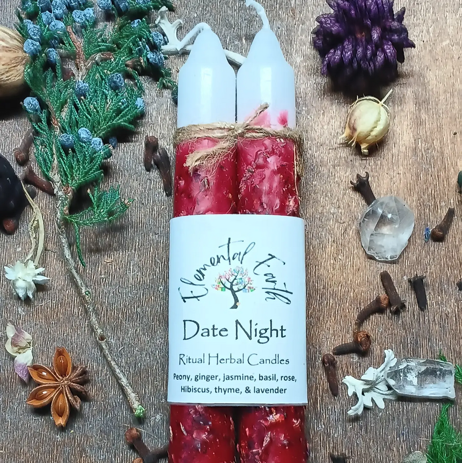 Two red ritual herbal candles labeled 'Date Night' with decorative elements on a wooden surface. Available at Luca Essentials in Los Angeles. 