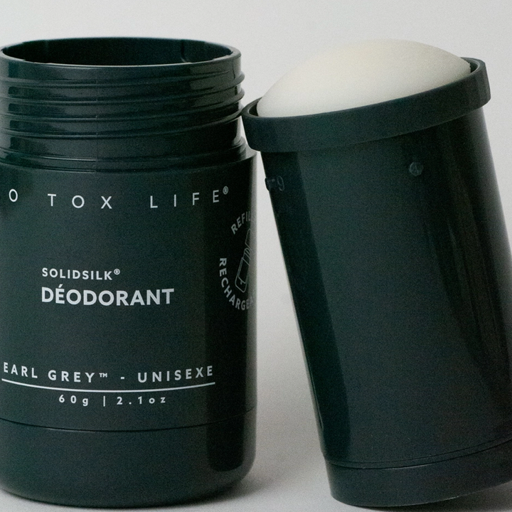 Two dark blue containers side by side, one empty with the branding 'no tox life' and a refill cartridge of deodorant leaning next to it on  white background. Available at Luca Essentials in Los Angeles. 