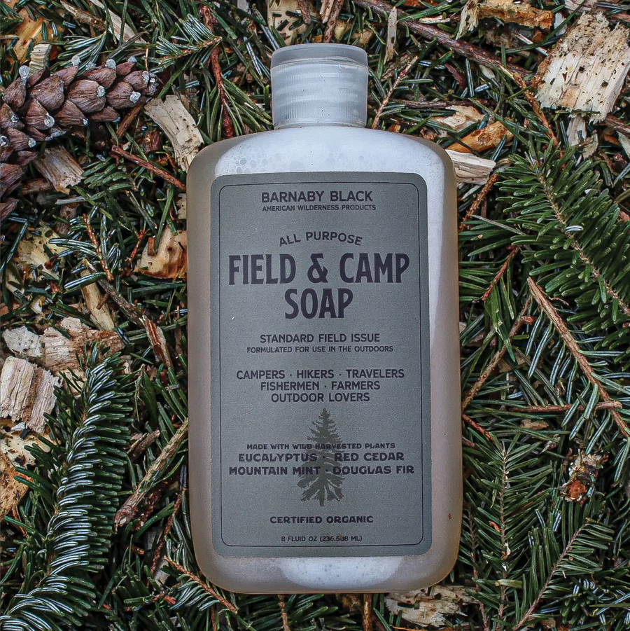 Bottle of Barnaby Black Field & Camp Soap on a natural background with pine needles and twigs. Available at Luca Essentials in Los Angeles. 