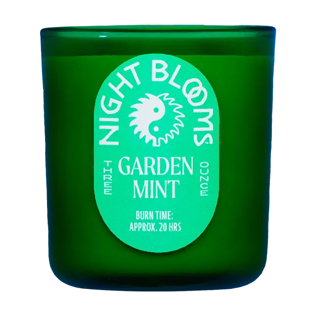 Dark green candle with 'Night Blooms' and "Garden Mint" label on a white background. Available at Luca Essentials in Los Angeles. 