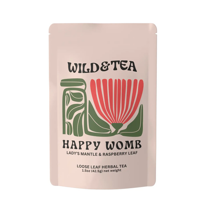 A stand-up pouch of Wild & Tea Happy Womb loose leaf herbal tea, featuring a light blush pink background with a stylized green and red botanical illustration. Available at Luca Essentials in Los Angeles. 