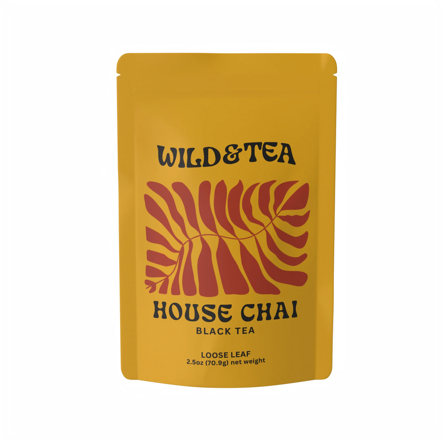A yellow stand-up pouch of Wild & Tea House Chai Black Tea loose leaf, featuring a red palm leaf graphic and black text, on a white background. Available at Luca Essentials in Los Angeles. 