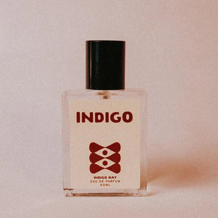 Perfume bottle labeled 'Indigo' on a light background with a black cap and red illustration on the label. Available at Luca Essentials in Los Angeles. 