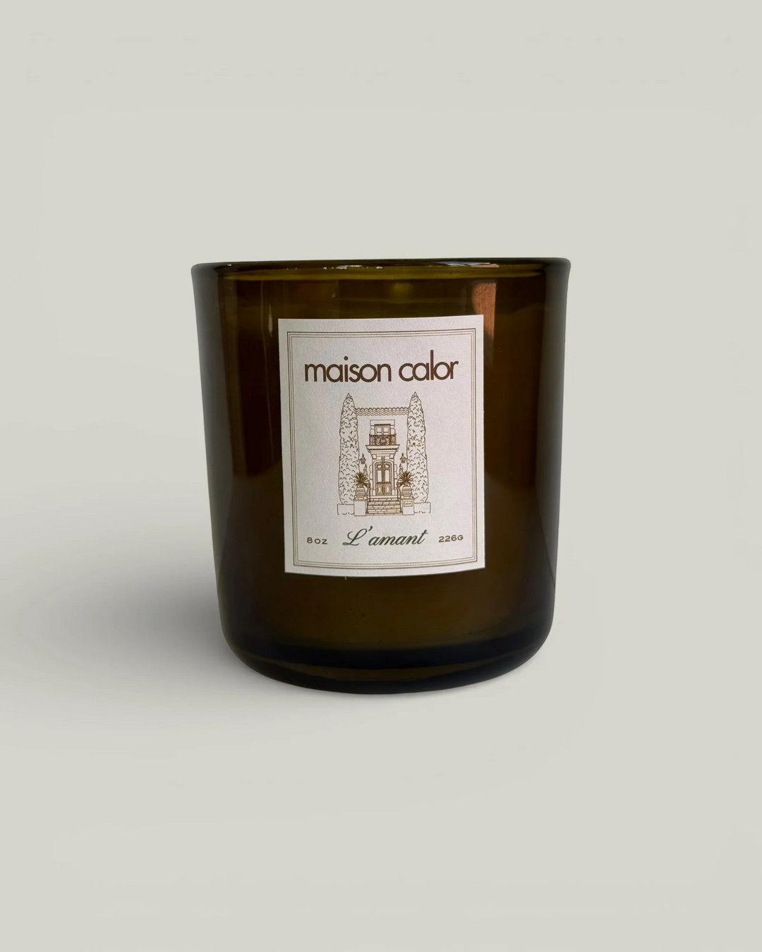 dark green glass candle container with the brand name 'maison calor' on a white sticker on a white background. Available at Luca Essentials in Los Angeles. 