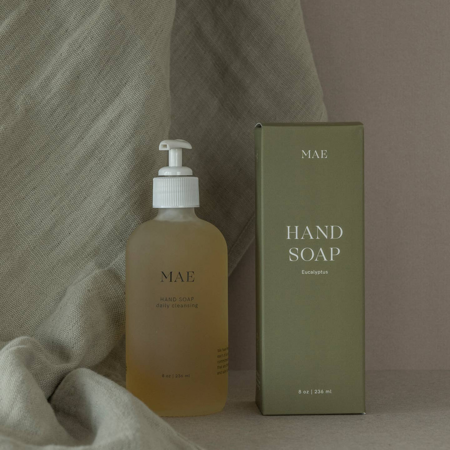 A glass bottle of Mae Hand Soap with a pump dispenser, next to its gray box packaging, on a marble surface.

Crafted with organic coconut, olive, and sunflower oils, this silky formula gently cleanses while replenishing the skin’s natural moisture barrier.

Available at Luca Essentials in Los Angeles. 