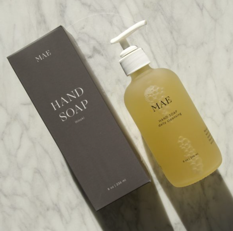 A glass bottle of Mae Hand Soap with a pump dispenser, next to its gray box packaging, on a marble surface.

Crafted with organic coconut, olive, and sunflower oils, this silky formula gently cleanses while replenishing the skin’s natural moisture barrier.

Available at Luca Essentials in Los Angeles.