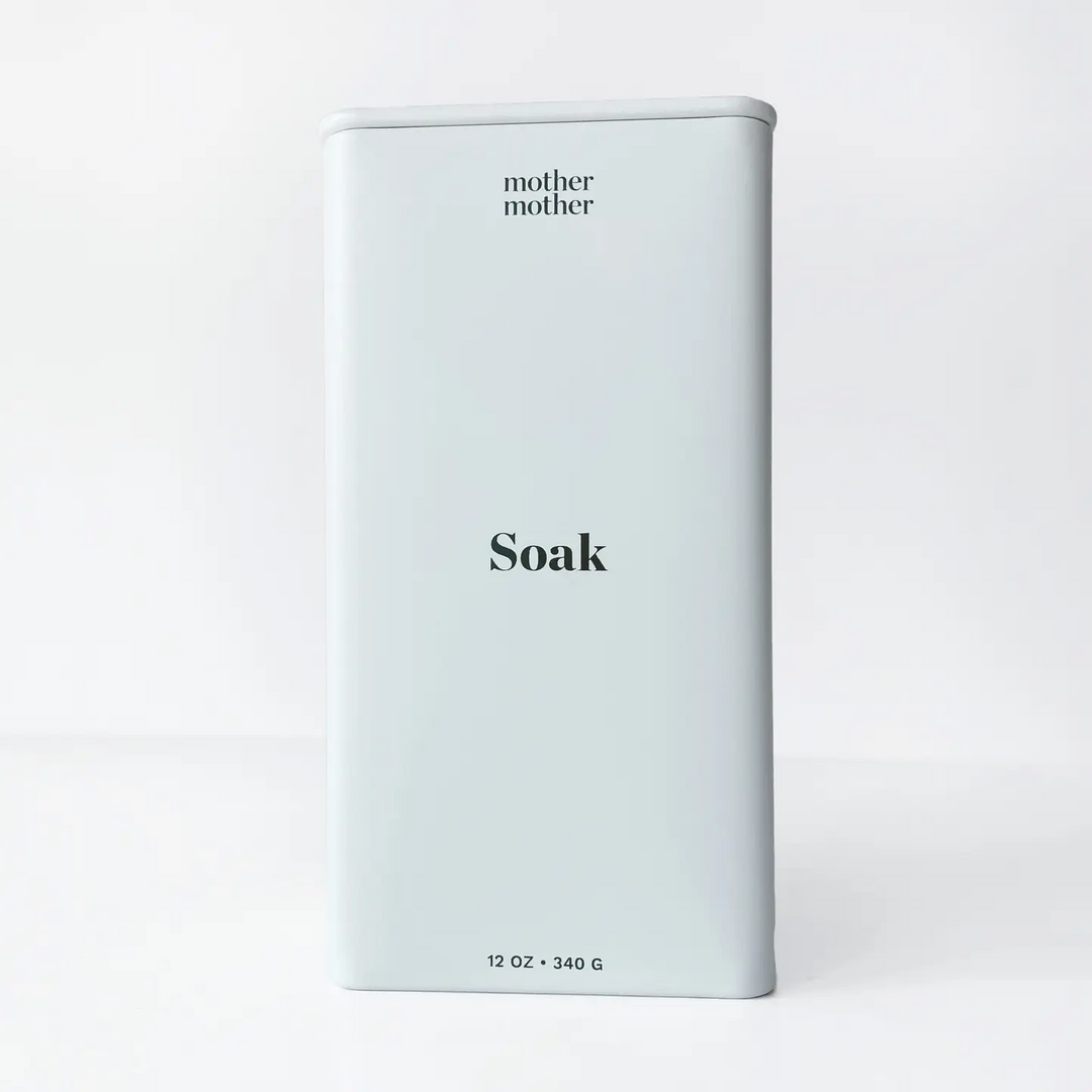 White metal container with 'mother mother' branding and 'Soak' text on a light gray background. Available at Luca Essentials in Los Angeles. 