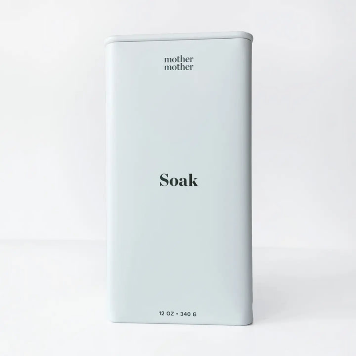 White metal container with 'mother mother' branding and 'Soak' text on a light gray background. Available at Luca Essentials in Los Angeles. 
