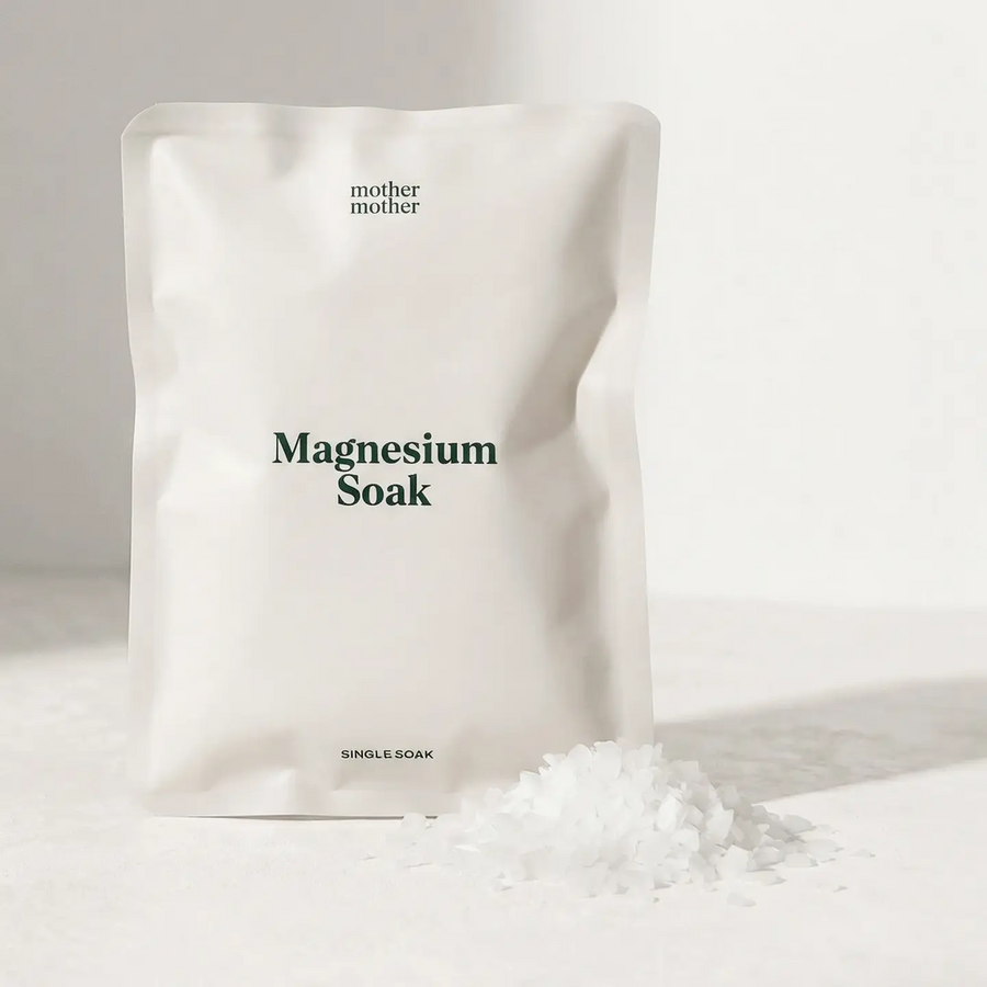 White bag labeled 'Magnesium Soak' by 'mother mother' on a light background with white magnesium flakes next to the white bag. Available at Luca Essentials in Los Angeles. 