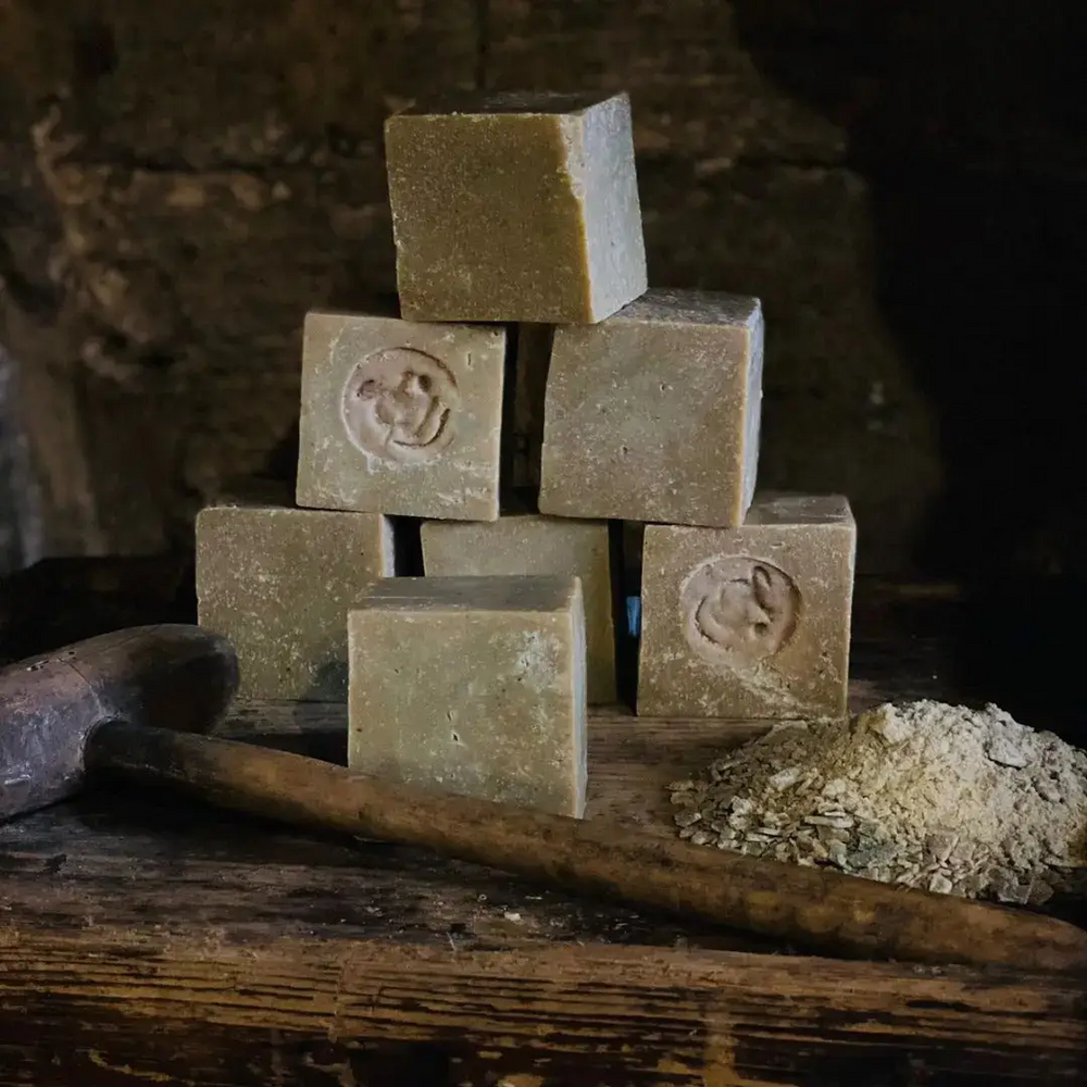 Stack of handmade soap bars with a rustic background. Available at Luca Essentials in Los Angeles. 
