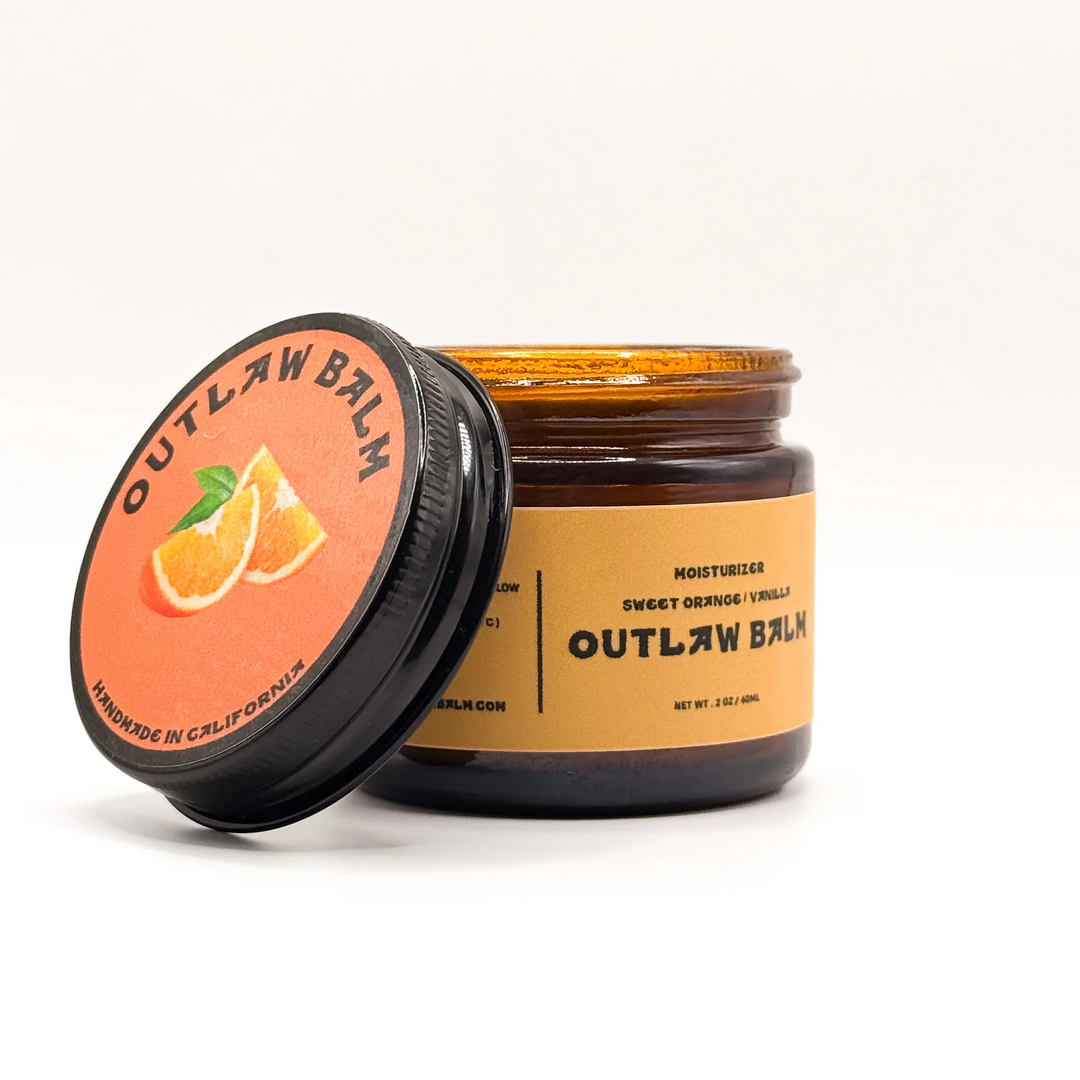 Outlaw Balm jar with orange label on a white background. Available at Luca Essentials in Los Angeles. 