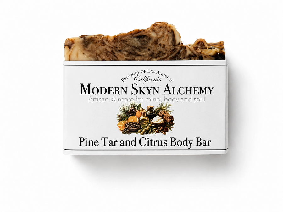 A brown and cream swirled bar of soap with a white sleeve that reads 'Modern Skyn Alchemy Pine Tar and Citrus Body Bar' on a white background. Available at Luca Essentials in Los Angeles. 