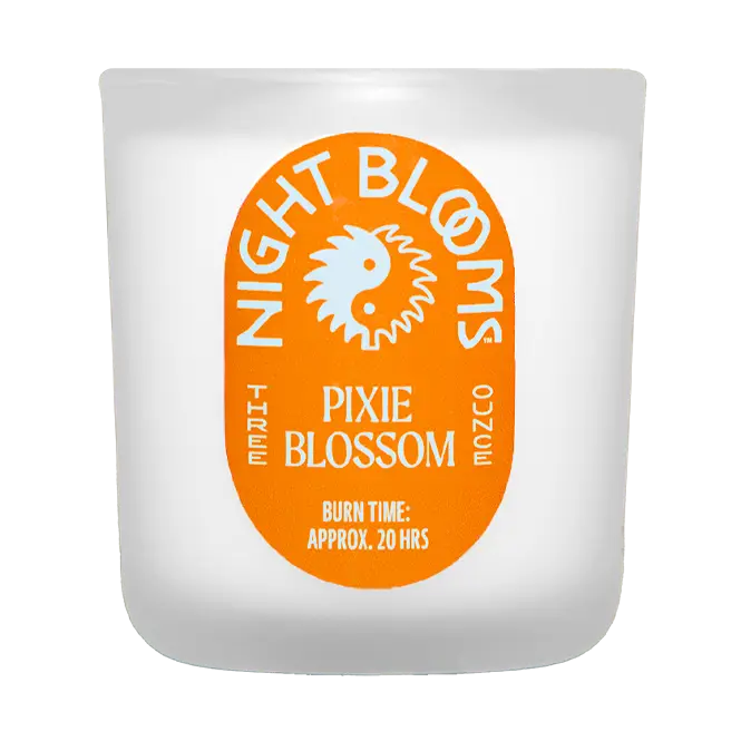 Candle with 'Night Blooms' and 'Pixie Blossom' orange label on a white background. Available at Luca Essentials in Los Angeles. 