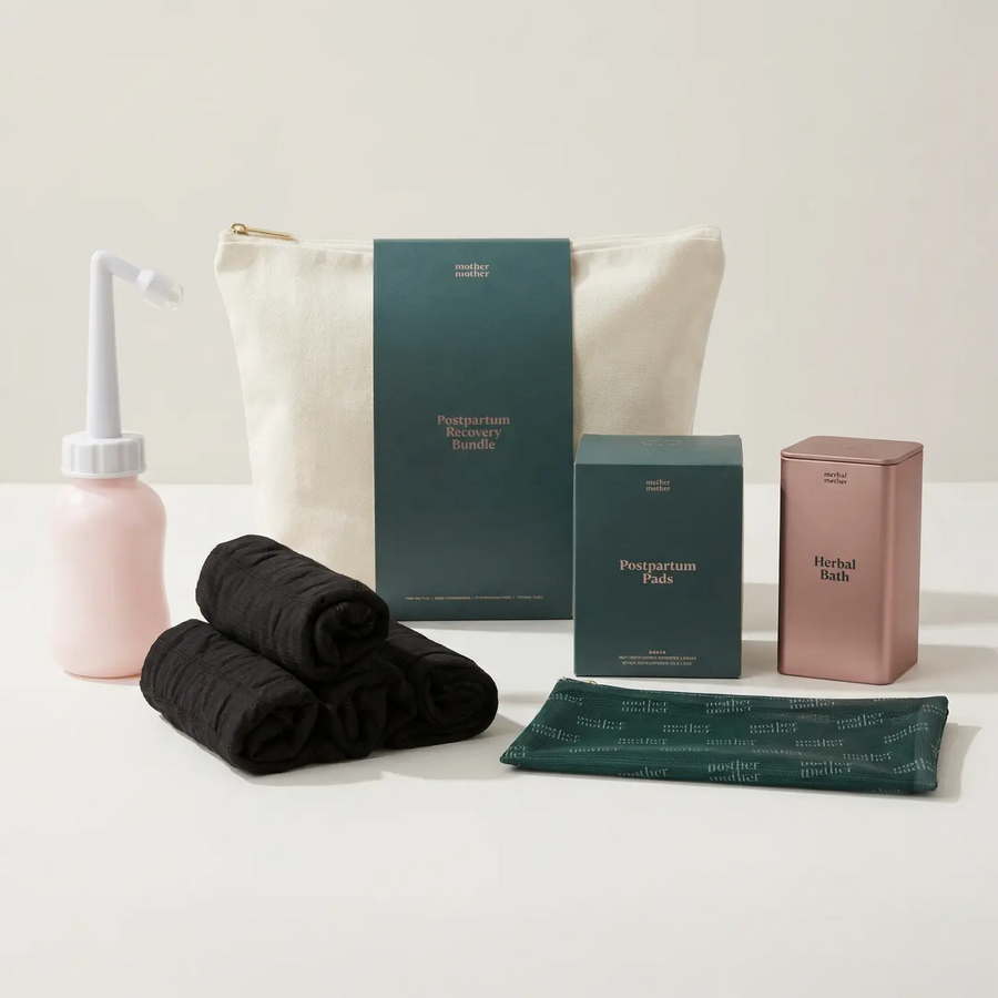 Postpartum recovery bundle canvas bag with green label, surrounded by one pink and white peri bottle, 5 black mesh underwear rolled up, a box of postpartum pads, a rose gold metal tin herbal bath and a mother mother branded carrying case. Available at Luca Essentials in Los Angeles. 