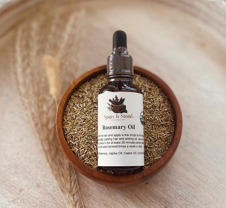Rosemary oil dropper bottle on a wooden bowl filled with rosemary leaves. Available at Luca Essentials in Los Angeles. 