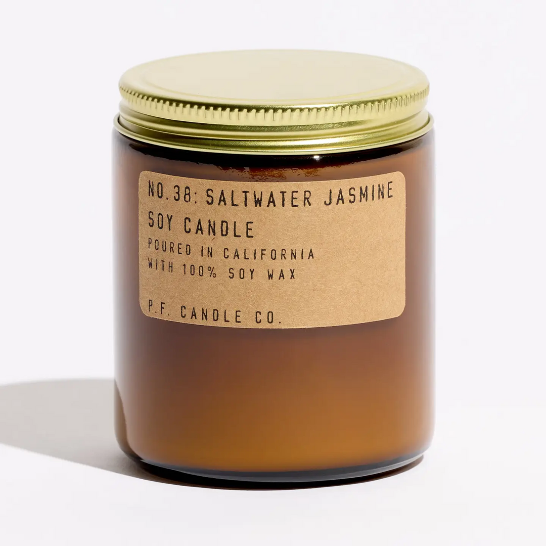 Amber glass candle with a gold lid and label on a white background. Available at Luca Essentials in Los Angeles. 
