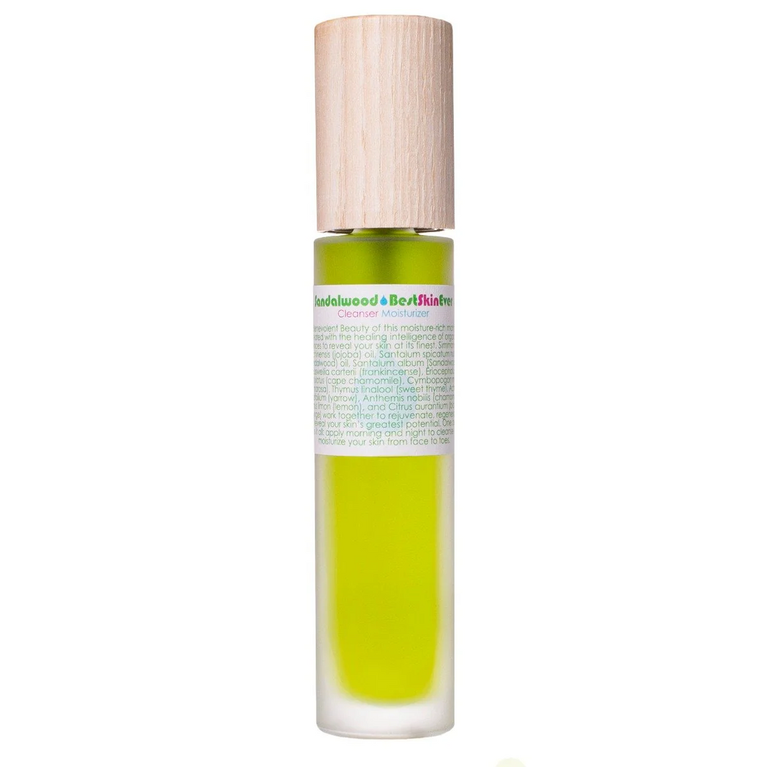 A clear glass bottle with a wooden cap, filled with a green liquid, labeled as 'Sandalwood Best Skin Ever' serum. Available at Luca Essentials in Los Angeles. 