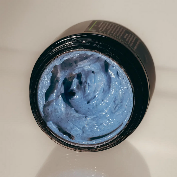 Open jar of blue cream cleanser with visible brand name on a beige background. Available at Luca Essentials in Los Angeles. 