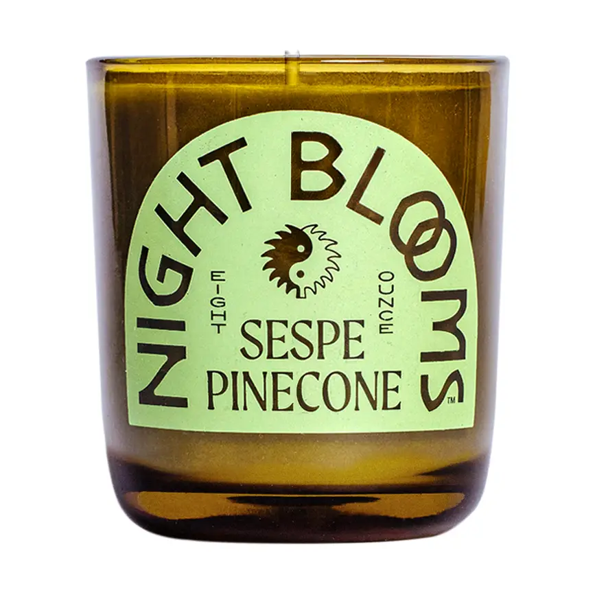 Candle with a label reading 'Night Blooms Sespe Pinecone' on a white background. Available at Luca Essentials in Los Angeles. 