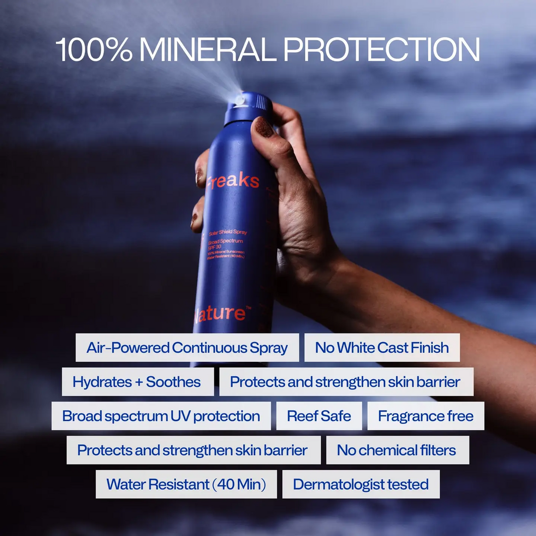 Hand holding a blue spray bottle labeled 'freaks of nature' with text about product features on a dark background. Available at Luca Essentials in Los Angeles. 