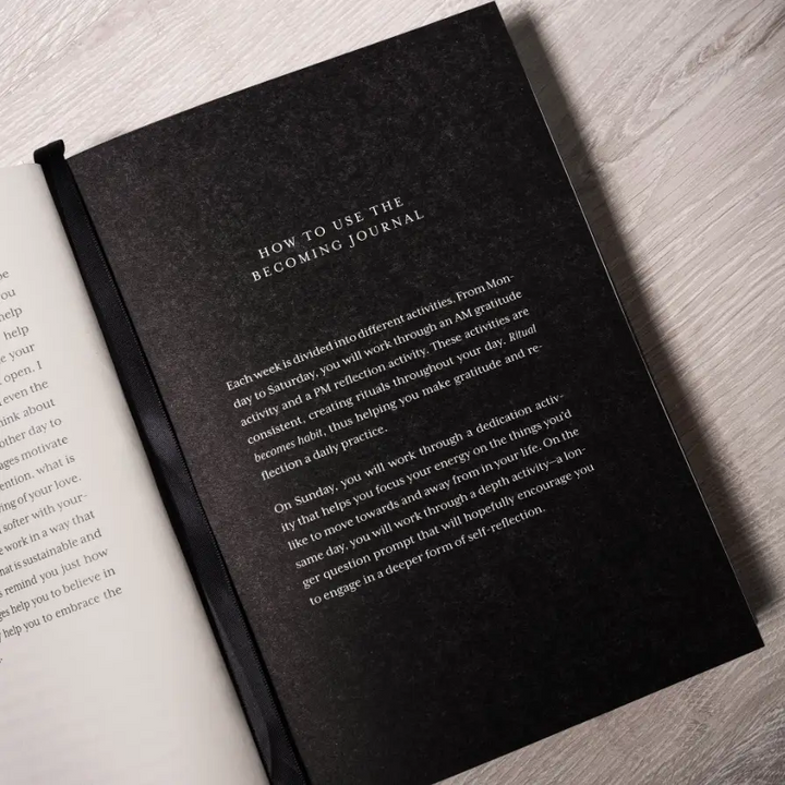 Black journal  page with text on a light wooden surface. Available at Luca Essentials in Los Angeles. 