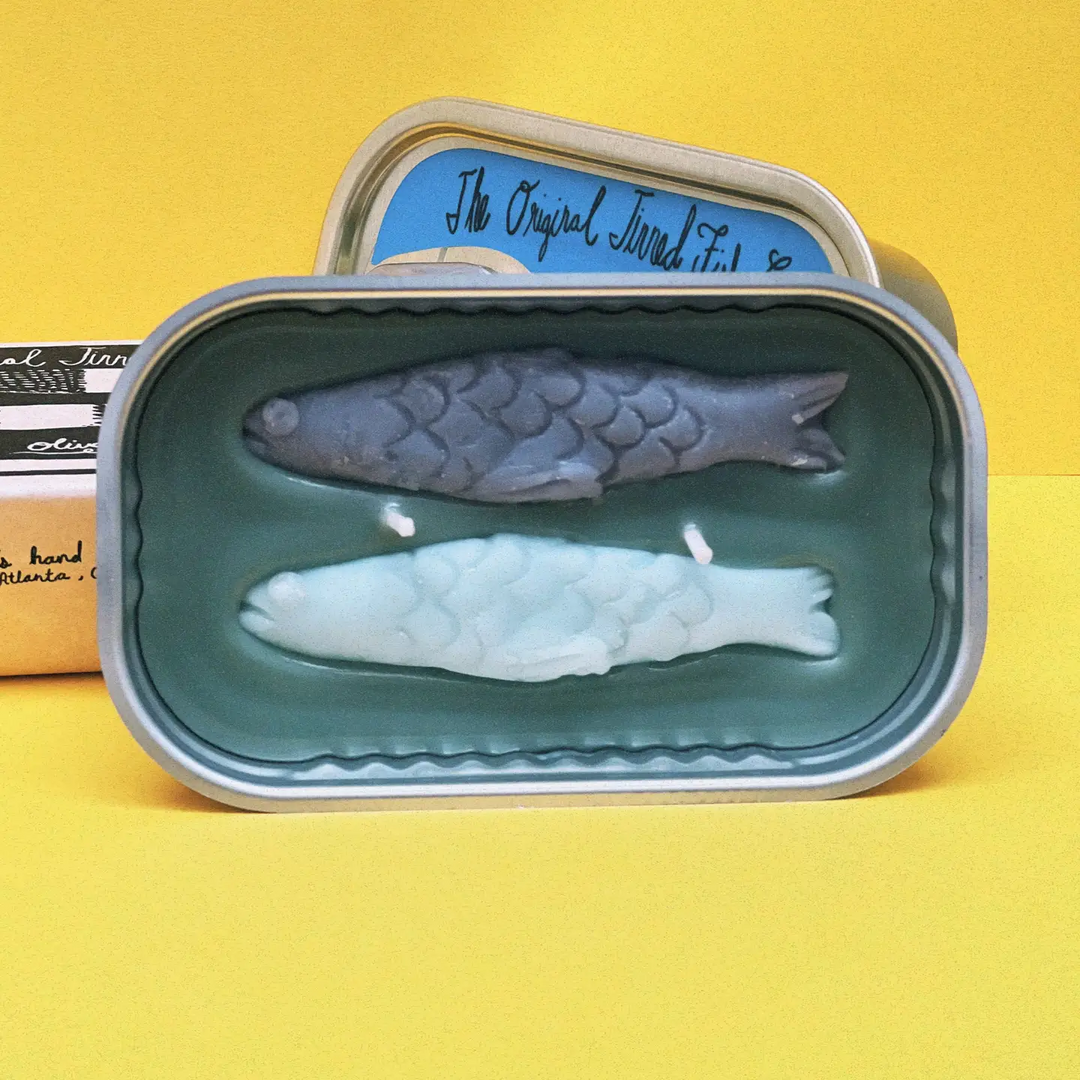 Two fish-shaped candles in a tin with a yellow background. Available at Luca Essentials in Los Angeles.