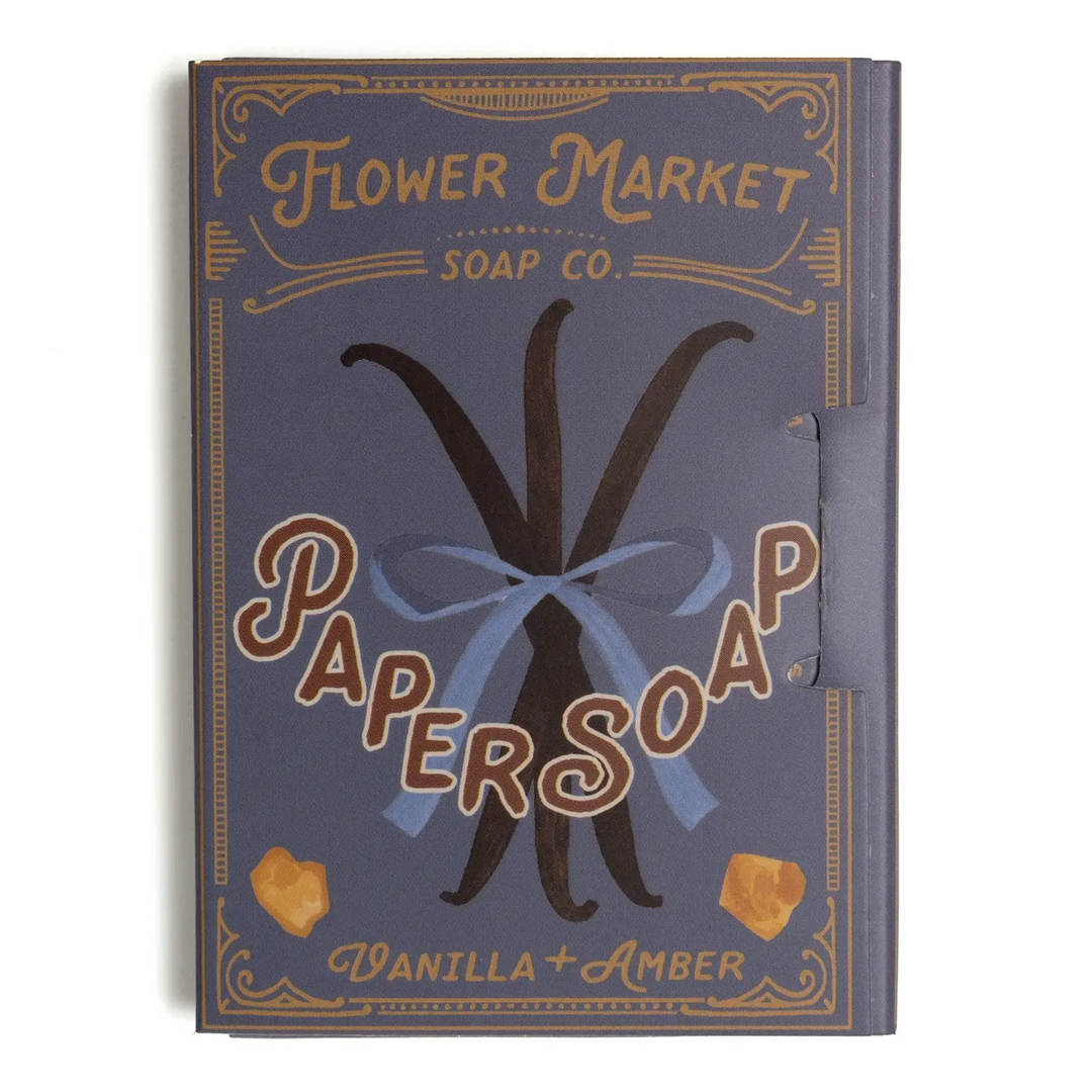 A rectangular soap bar package or box cover for 'Flower Market Soap Co.'s 'Paper Soap' in the 'Vanilla + Amber' scent. Available at Luca Essentials in Los Angeles. 