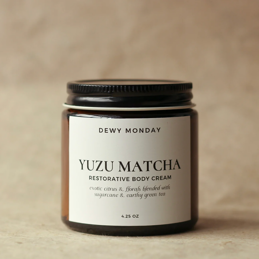 Yuzu Matcha restorative body cream jar with 'Dewy Monday' label on a beige background. Available at Luca Essentials in Los Angeles. 
